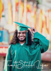 a man in a green graduation gown is posing for a photo